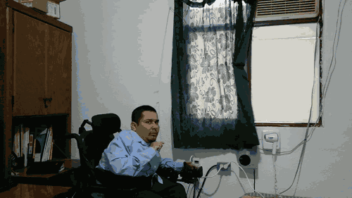 Una persona en silla de ruedas abriendo una cortina de forma adaptada